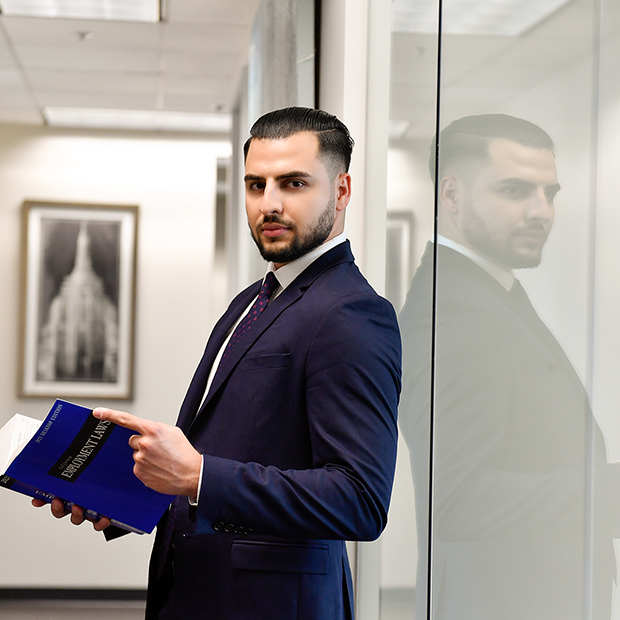 Amiel Azizollahi lawyer in the Equate Law offices holding an employment law book.